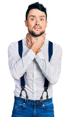 Poster - Hispanic man with beard wearing hipster look with bow tie and suspenders shouting and suffocate because painful strangle. health problem. asphyxiate and suicide concept.