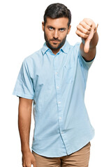 Wall Mural - Handsome hispanic man wearing casual clothes looking unhappy and angry showing rejection and negative with thumbs down gesture. bad expression.