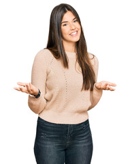 Poster - Young brunette woman wearing casual winter sweater smiling cheerful with open arms as friendly welcome, positive and confident greetings