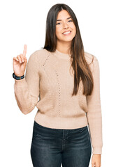 Poster - Young brunette woman wearing casual winter sweater showing and pointing up with finger number one while smiling confident and happy.