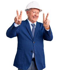 Canvas Print - Senior handsome grey-haired man wearing suit and architect hardhat smiling looking to the camera showing fingers doing victory sign. number two.