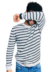 Sticker - Young arab man with beard wearing casual striped sweater covering eyes with arm smiling cheerful and funny. blind concept.