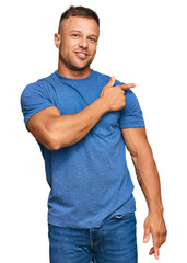 Canvas Print - Handsome muscle man wearing casual clothes cheerful with a smile of face pointing with hand and finger up to the side with happy and natural expression on face