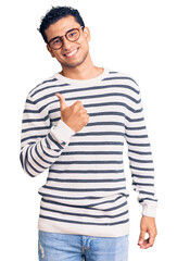 Sticker - Hispanic handsome young man wearing casual clothes and glasses doing happy thumbs up gesture with hand. approving expression looking at the camera showing success.