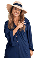 Sticker - Middle age hispanic woman wearing summer hat cheerful with a smile of face pointing with hand and finger up to the side with happy and natural expression on face