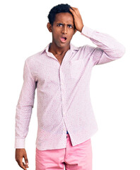 Canvas Print - African handsome man wearing casual pink shirt surprised with hand on head for mistake, remember error. forgot, bad memory concept.