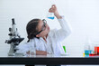 © chomplearn_2001 - Preteen caucasian girl wearing glasses and lab coat looking science test glass, chemical experiment in laboratory at school