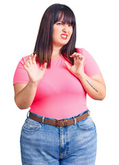 Canvas Print - Young plus size woman wearing casual clothes disgusted expression, displeased and fearful doing disgust face because aversion reaction. with hands raised