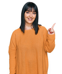 Poster - Young hispanic woman wearing casual clothes with a big smile on face, pointing with hand finger to the side looking at the camera.