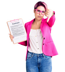 Poster - Young beautiful woman with pink hair holding clipboard with contract document looking unhappy and angry showing rejection and negative with thumbs down gesture. bad expression.