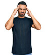 © Krakenimages.com - Young hispanic man wearing casual clothes suffering from headache desperate and stressed because pain and migraine. hands on head.