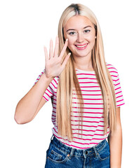 Wall Mural - Beautiful blonde woman wearing casual striped t shirt showing and pointing up with fingers number five while smiling confident and happy.