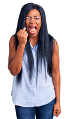 Wall Mural - Young african american woman wearing casual clothes angry and mad raising fist frustrated and furious while shouting with anger. rage and aggressive concept.