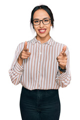 Wall Mural - Young hispanic girl wearing casual clothes and glasses pointing fingers to camera with happy and funny face. good energy and vibes.