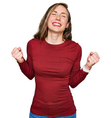 Canvas Print - Young blonde woman wearing casual clothes very happy and excited doing winner gesture with arms raised, smiling and screaming for success. celebration concept.