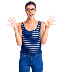 Wall Mural - Young beautiful woman wearing casual clothes and glasses celebrating crazy and amazed for success with arms raised and open eyes screaming excited. winner concept