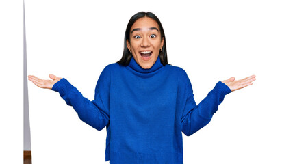 Poster - Young asian woman wearing casual winter sweater celebrating victory with happy smile and winner expression with raised hands