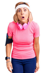 Canvas Print - Young blonde woman wearing sportswear and headphones scared and amazed with open mouth for surprise, disbelief face