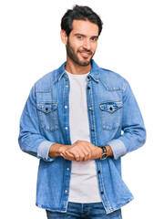 Young hispanic man wearing casual clothes with hands together and crossed fingers smiling relaxed and cheerful. success and optimistic