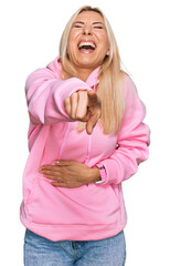 Wall Mural - Young blonde woman wearing casual sweatshirt laughing at you, pointing finger to the camera with hand over body, shame expression