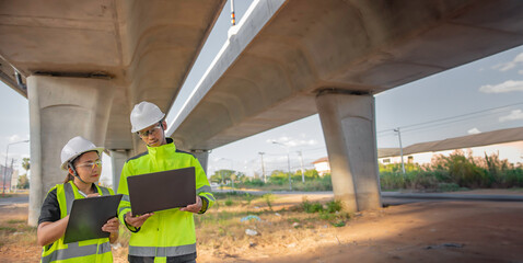 Two engineers discuss about work at the site of large bridge under construction,Management consulting people discussion with engineers about the progress and construction planning of highway