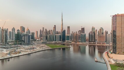 Wall Mural - Aerial view to Dubai Business Bay and Downtown during sunset with the various skyscrapers and towers along waterfront on canal timelapse. Construction site with cranes