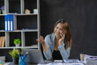 © ArLawKa - Asian businesswoman holding smartphone in talking with business clients with charts or documents in workplace using calculator, business laptop, financial accountant calculating money, loan bank,