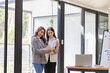 © ArLawKa - Two asian businesswoman sitting and consulting business inside modern office discussing presentation of startup project idea Analyze statistics and investment markets at the office.