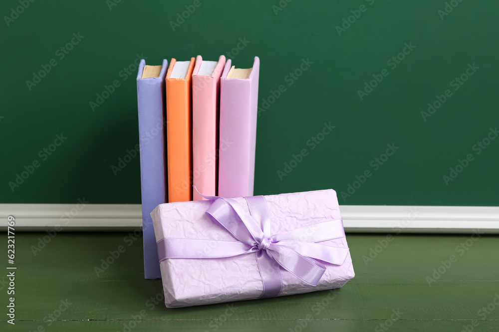 Gift box with different books on table in classroom