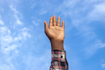 An evocative scene of a Christian pastor, his figure silhouetted against the blue sky, his hands outstretched, passionately imploring Jesus for spiritual strength and direction.