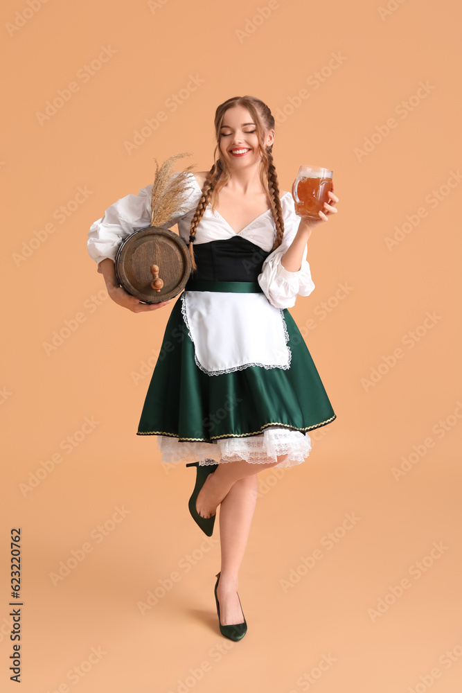 Beautiful Octoberfest waitress with beer and barrel on beige background