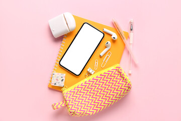 Wall Mural - Stationery with mobile phone and earphones on pink background