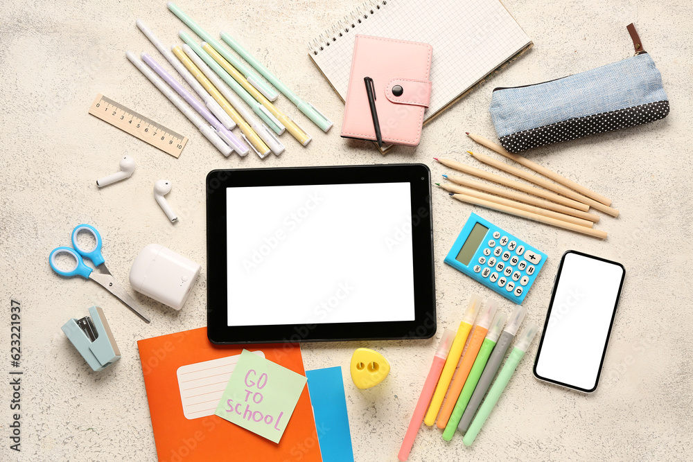 Sticky note with text GO TO SCHOOL, gadgets and different stationery on grunge white background