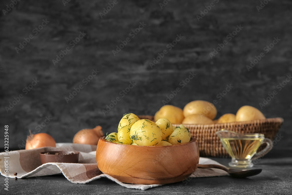Bowl with boiled baby potatoes on black background