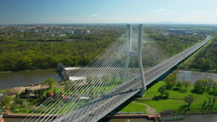 Wall Mural - Massive pylon bridge spanning Oder river flowing by Wroclaw. Redzinski Bridge and lush greenery around city of Poland on sunny day aerial view