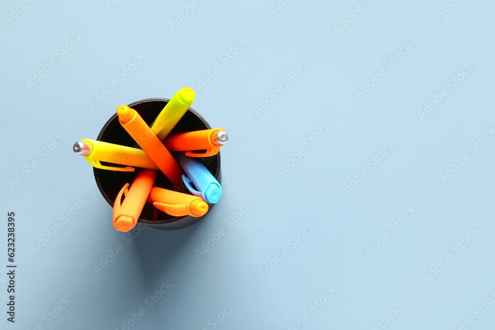 Cup with colorful pens on grey background