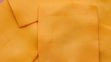 Wall Mural - slices of yellow cheddar cheese, rotation in circle. Square slices of processed cheese for a burger, Turning. selective focus.