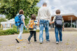 © Elena Medoks - View from the back of a happy parent who escorts his children sons and daughter to school. Back to school. Father's care for children.