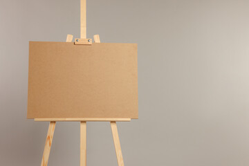 Wooden easel with blank board on grey background. Space for text