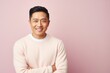 © Leon Waltz - Portrait of a smiling asian man standing with arms folded against pink background