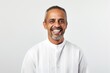 © Anne Schaum - Medium shot portrait photography of a happy Saudi Arabian man in his 50s wearing a chic cardigan against a white background