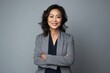© Anne Schaum - Portrait of a smiling businesswoman standing with arms crossed against grey background