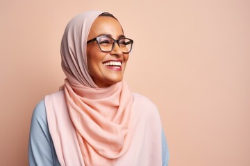 Lifestyle portrait photography of a happy Saudi Arabian woman in her 50s wearing a chic cardigan against a pastel or soft colors background 