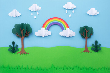 paper art landscape background. rainbow on blue sky with clouds and green tree made of paper cut. cr
