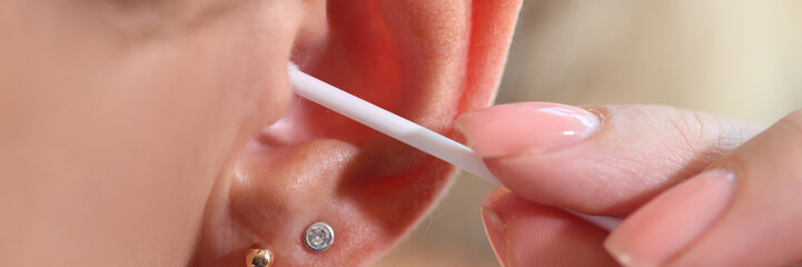 Woman cleaning her ear with cotton swab, people hygiene concept.