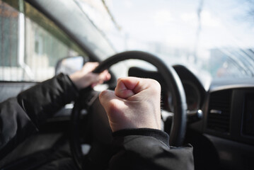 Wall Mural - Angry driver is shaking by his fist sitting by the car steering wheel.