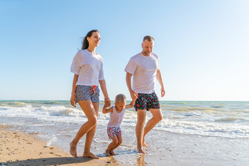 family with little son walk along seashore on a sunny day, the concept of family and vacation