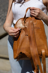 Wall Mural - girl in white leggings and T-shirt with a light brown leather backpack in her hands