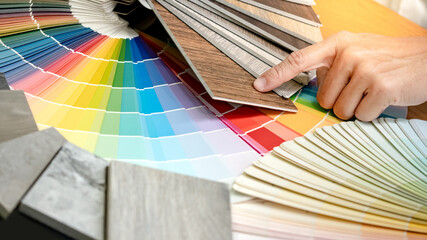 Wall Mural - Designer hand choosing and pointing at wood laminate material samples with color swatch and wooden tile texture collection nearby. Catalog guide for interior architecture and furniture design work