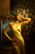 Art photo strong face girl high fashion model posing in luxury room. gold long silk evening dress trendy style gown. Sexy elegant woman golden makeup shine skin metal color paint. fantasy glam queen.